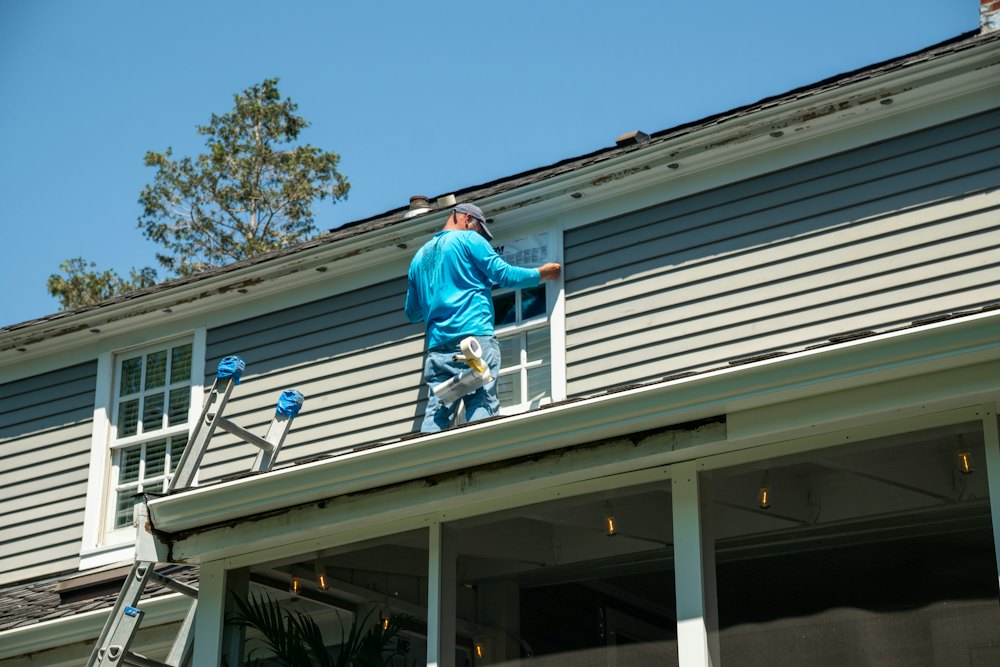 Roofer working on the roof of a gray house