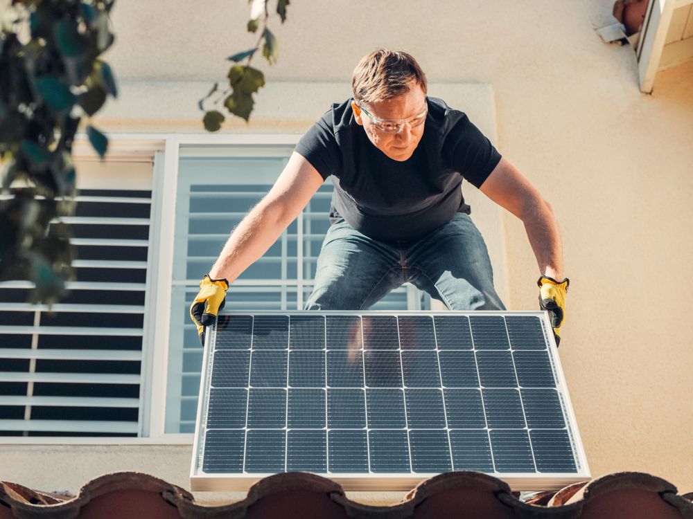 Installer fitting a solar panel on a house roof